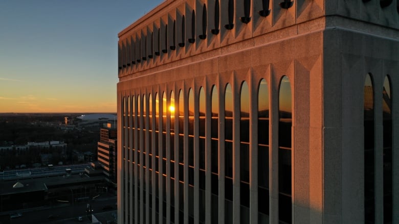 The reflection of the sun set can be seen in the windows of a multi-story building. 