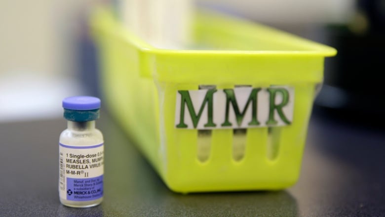 A vaccine vial is shown to the left of a bin labelled 