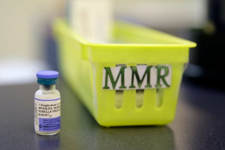 A vaccine vial is shown to the left of a bin labelled 