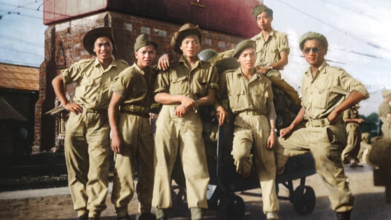 A group of Chinese Canadian soldiers pose next to supply crates.