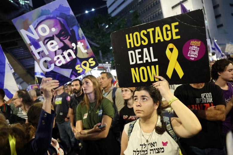 Protesters hold up signs calling for a hostage deal.