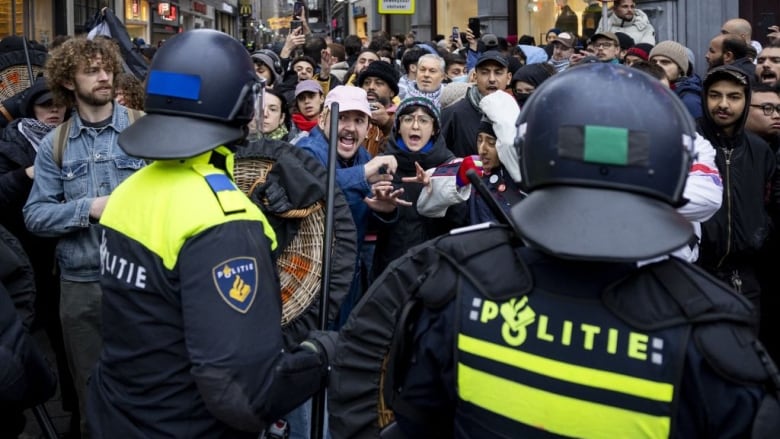 Police block a crowd of protesters on the street.