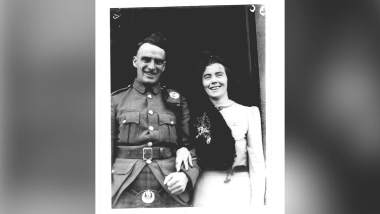 A black and white photo of a couple standing together, smiling.