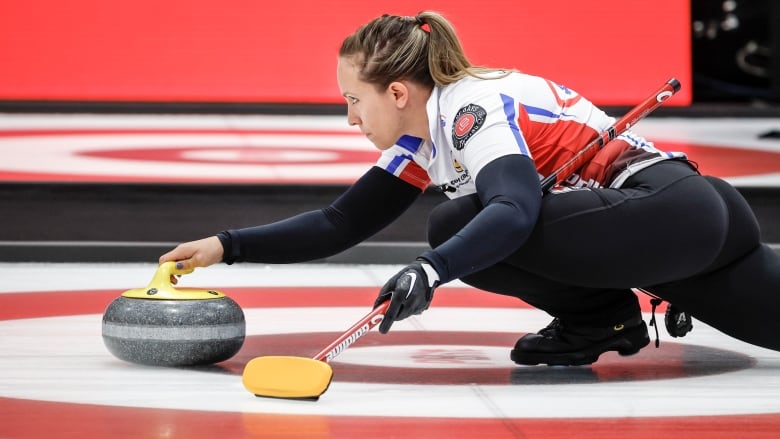 A woman curler throws a stone.