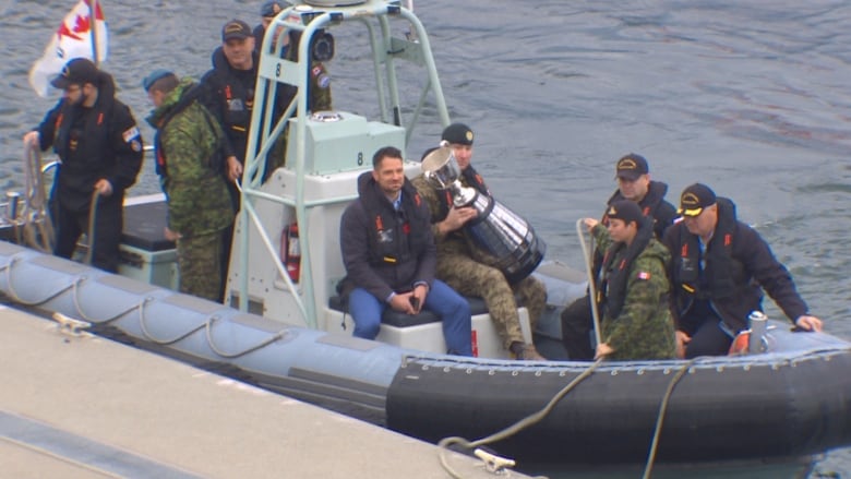 A flotilla with a bunch of people in military uniforms dock at a harbour.