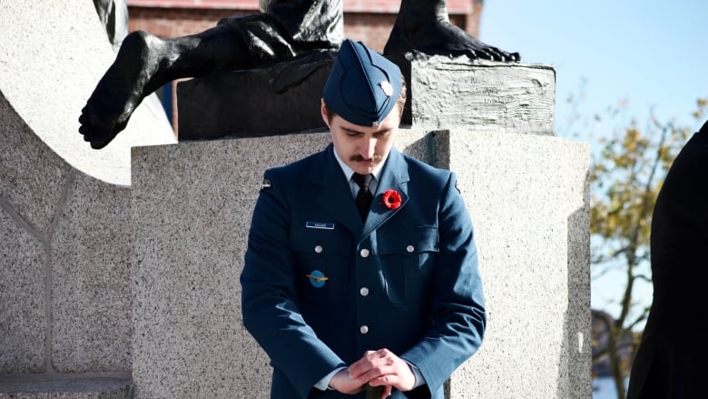 Man in uniform bowing head at memorial