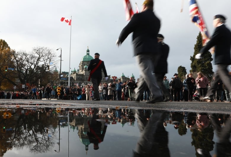 A procession of soldiers march toward the legislature, in front of a crowd