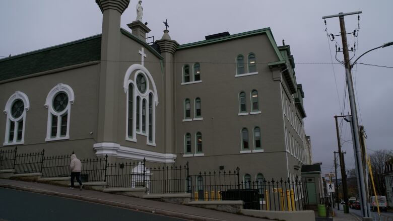 A large, grey four-story building with a cross at the top.