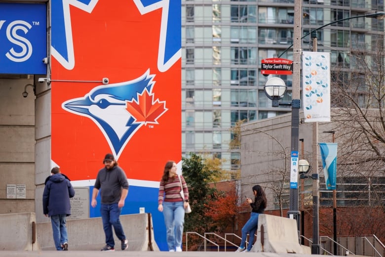 People take pictures near a newly erected Taylor Swift Way street sign outside Rogers Centre in Toronto.