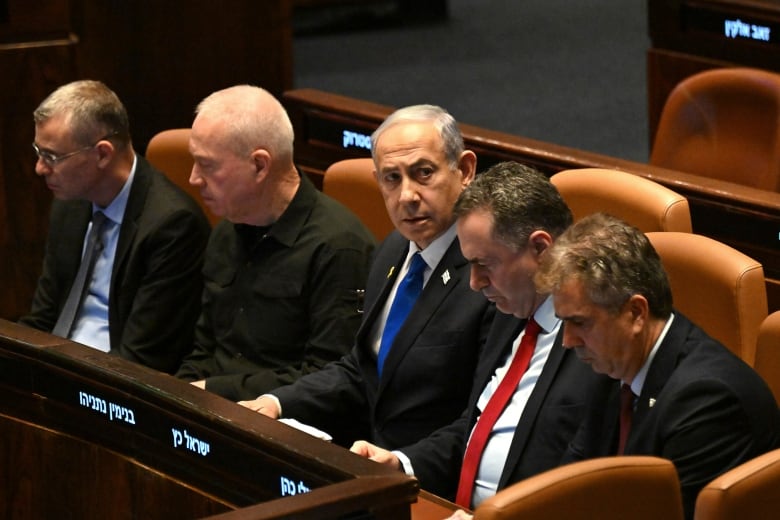 Five men in suits sit at a wooden desk.