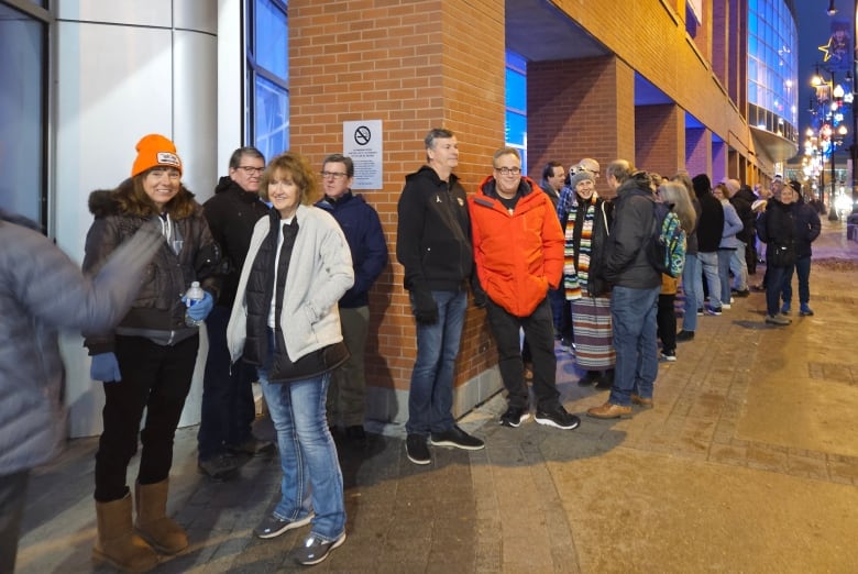 People line up outside a building to get inside