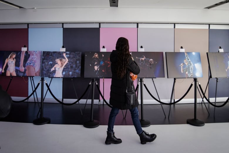 A person walks and looks at a Taylor Swift photo exhibit at the CN Tower's main observation deck.