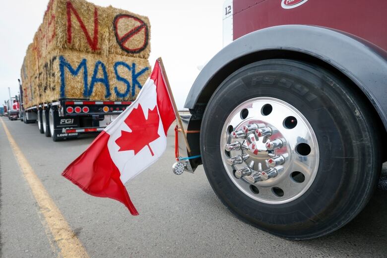 The Canadian flag is reflected in a wheel hub of a vehicle with a haybale painted with 