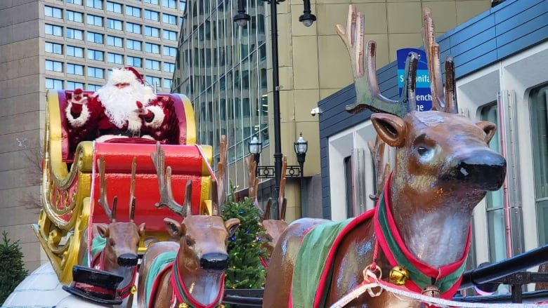 Santa Claus waves from his sleigh to a crowd watching a parade