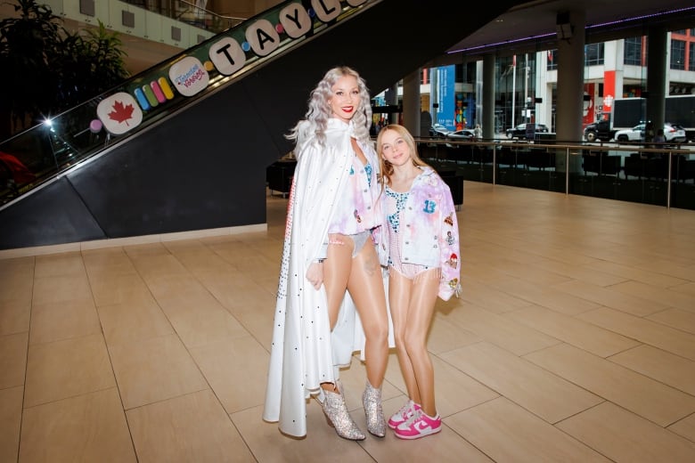 In Taylor Swift inspired outfits, a blond mom and daughter smile for portraits at the Taylgate '24 event ahead of the Taylor Swift Eras Tour concert.