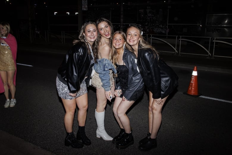 Four young women dressed in sequin outfits outside Rogers Centre, ahead of the Taylor Swift Eras tour concert.