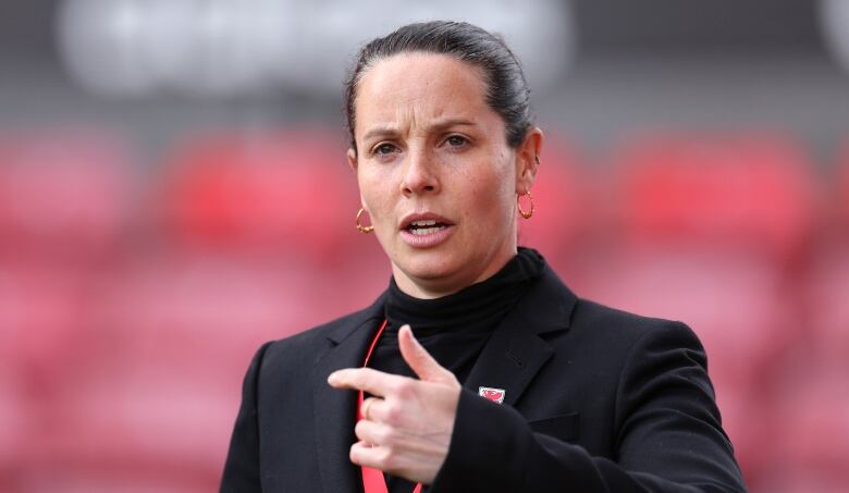 A woman's soccer coach gestures prior to a game.