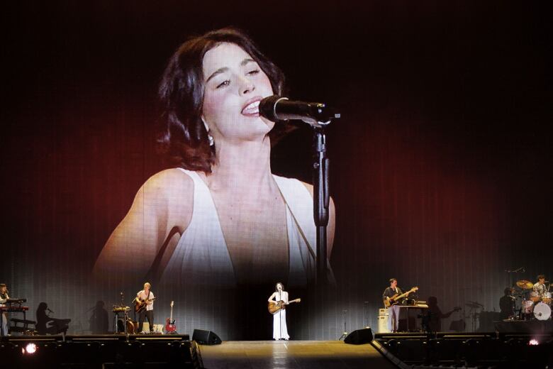 On stage with backup musicians, Gracie Abrams sings during the opening act for Taylor Swift