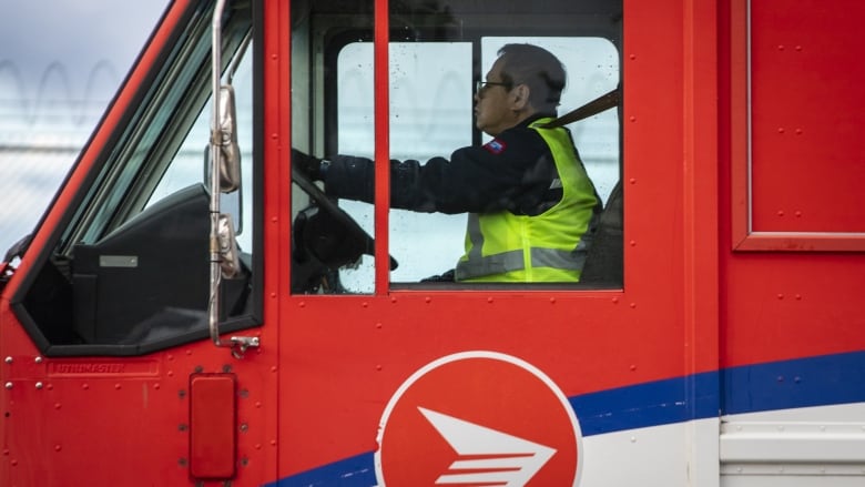 A delivery person drives a Canada post truck