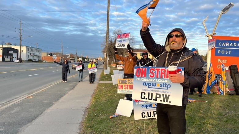 a man with a sign stands on the side of a roadway