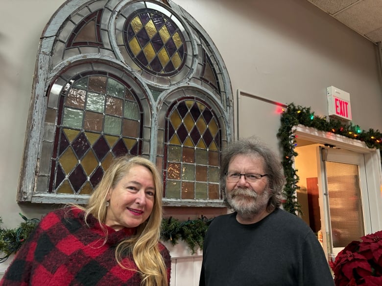 two people in front of a large stained glass window