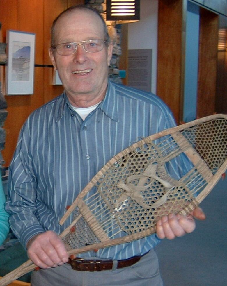 Smiling man holding snowshoe