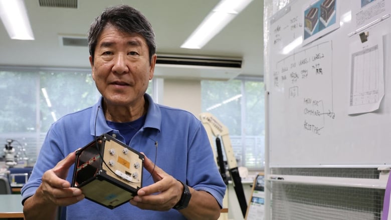 A man is pictured holding a small wooden box. 