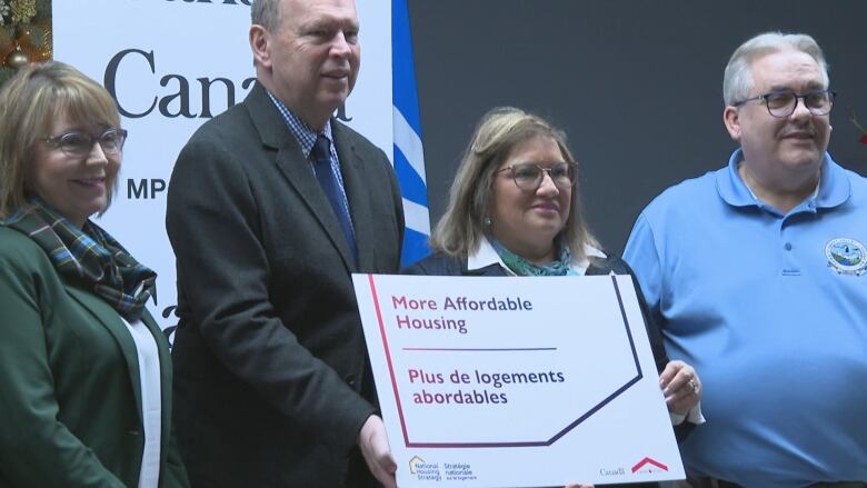 Four people hold a sign.