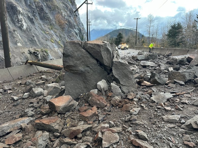 A huge rock and several smaller ones on a highway.