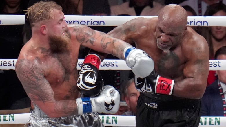 A man punches another man in a professional boxing ring.