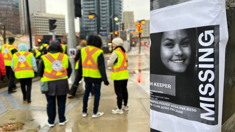 A poster with a missing woman's face is on a black pole.