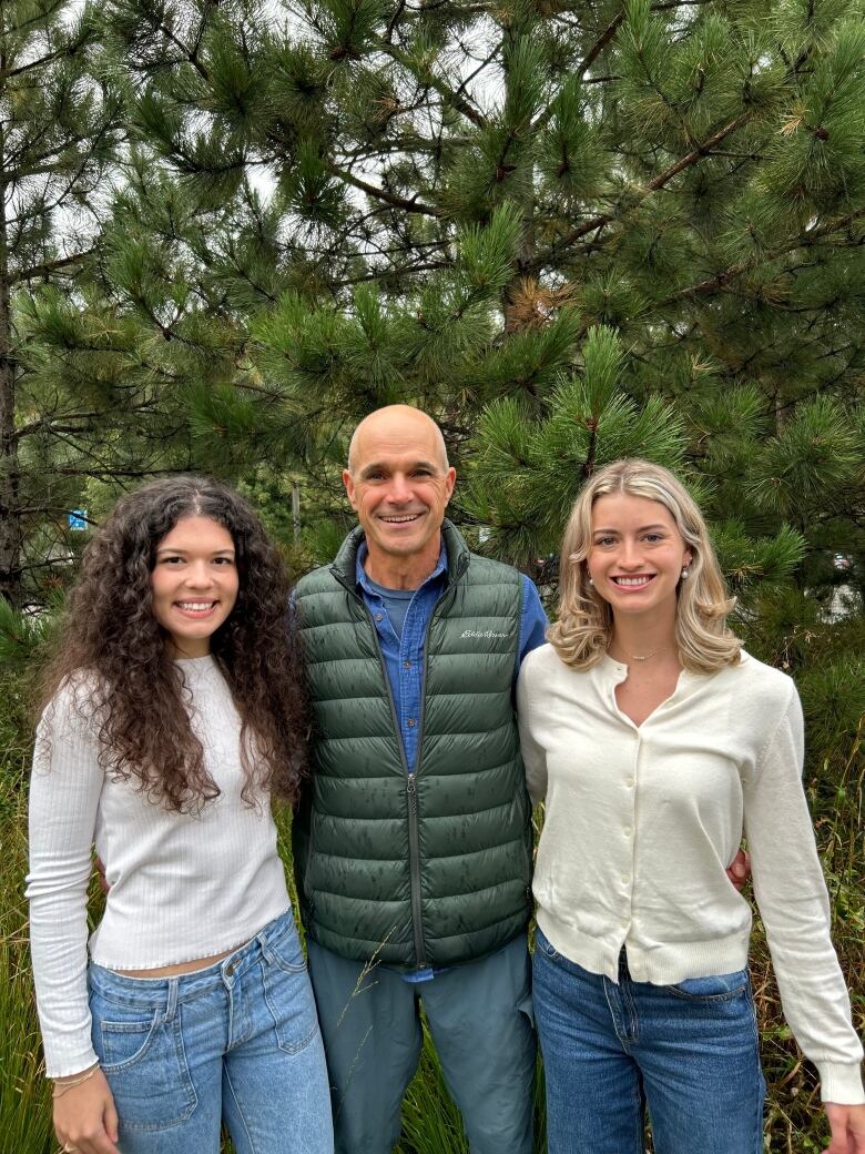 A bald man and two younger women posing for a photo.