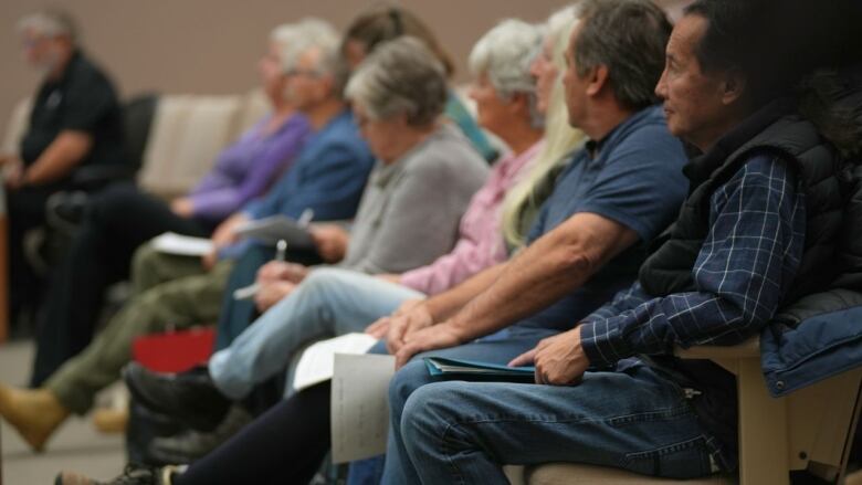 a row of people sit in chairs.