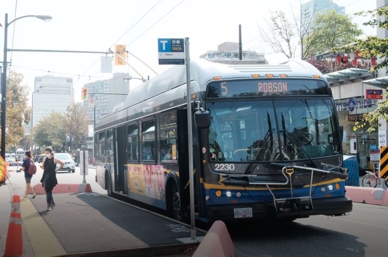 A bus drops off passengers at an extended curb.