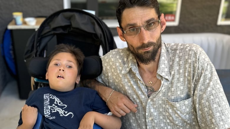 A young boy and his dad look at the camera.