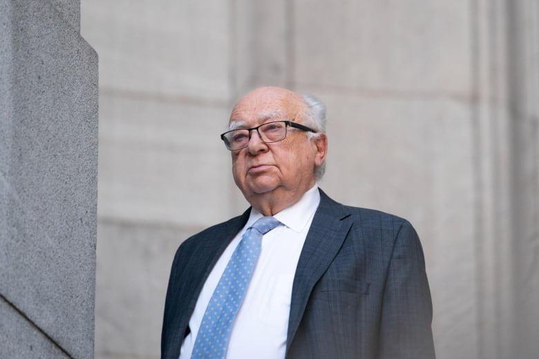 Man with blue tie in front of a building. 