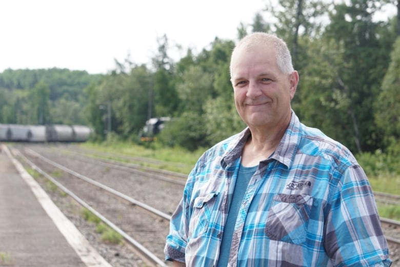 A man in a checkered shirt smiles at the camera. 