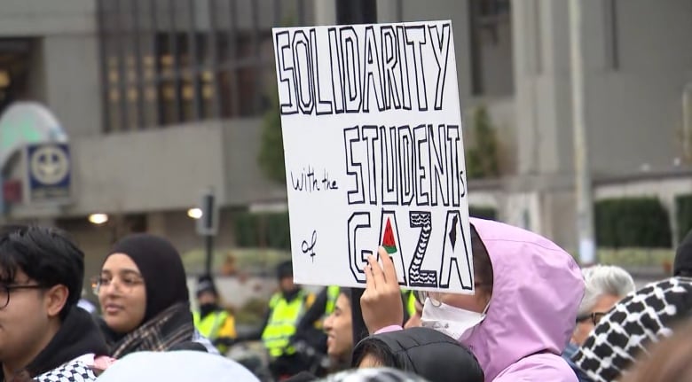 A young woman holds a sign that says 