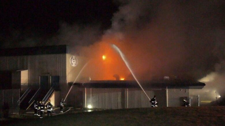 Multiple firefighters spray suppressant on a fire at a school.