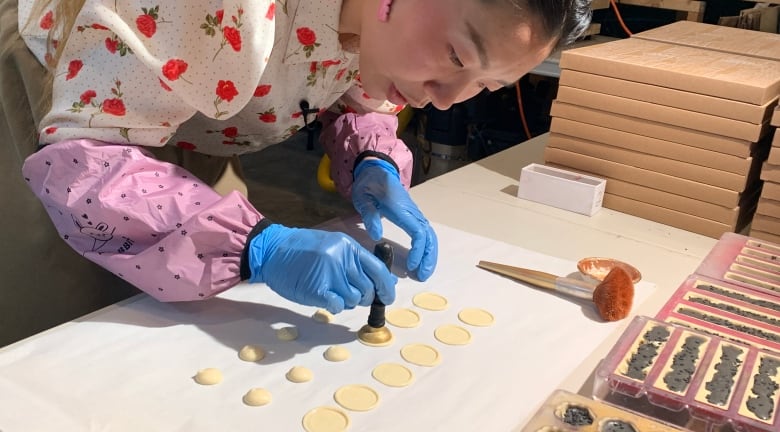 A woman stamps her logo into small piles of white chocolate.