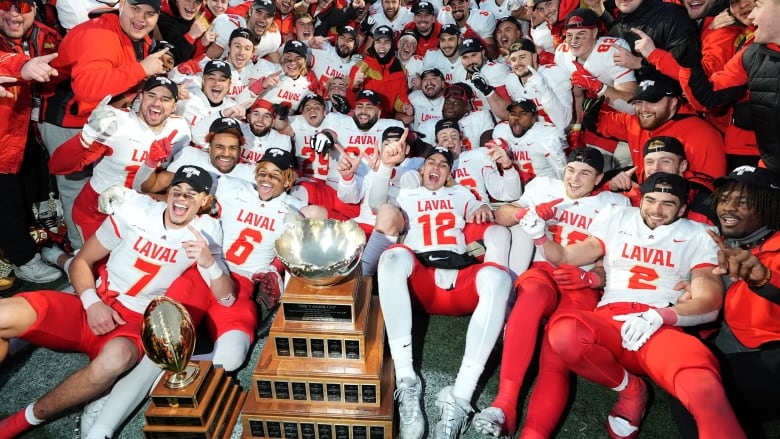 Laval University Rouge et Or players pose for photos with the trophy as they celebrate their win over Laurier Golden Hawks after U Sports Vanier Cup football action in Kingston, Ontario on Saturday, Nov. 23, 2024. 