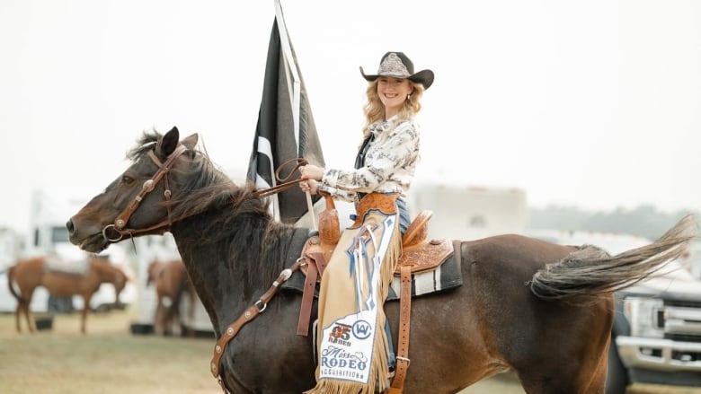 A women sitting on a horse in a cowboy hat.