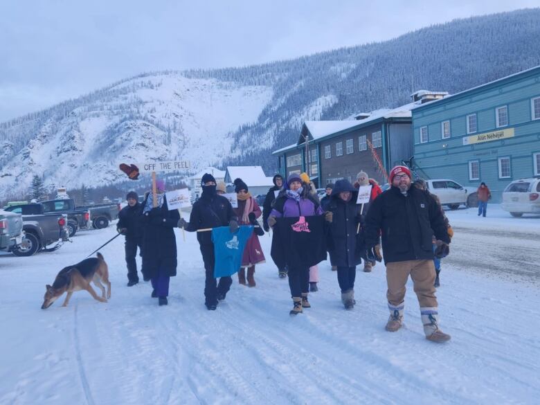 People with shirts and signs rally outside on a cold winter day 