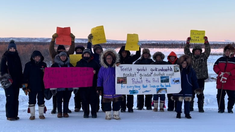 About 15 people are pictured rallying holding signs that say things like 'protect the Peel.'