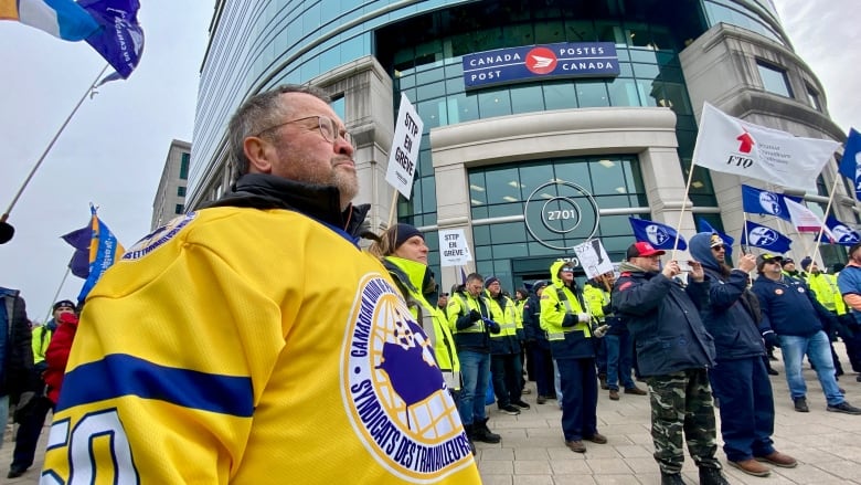 A man in a yellow shirt outside the Canada Post building.