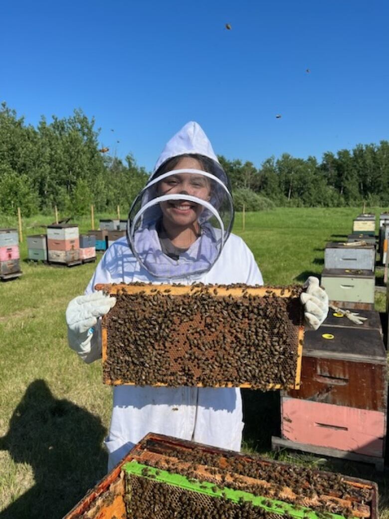 A photo of a young women holding bees. 